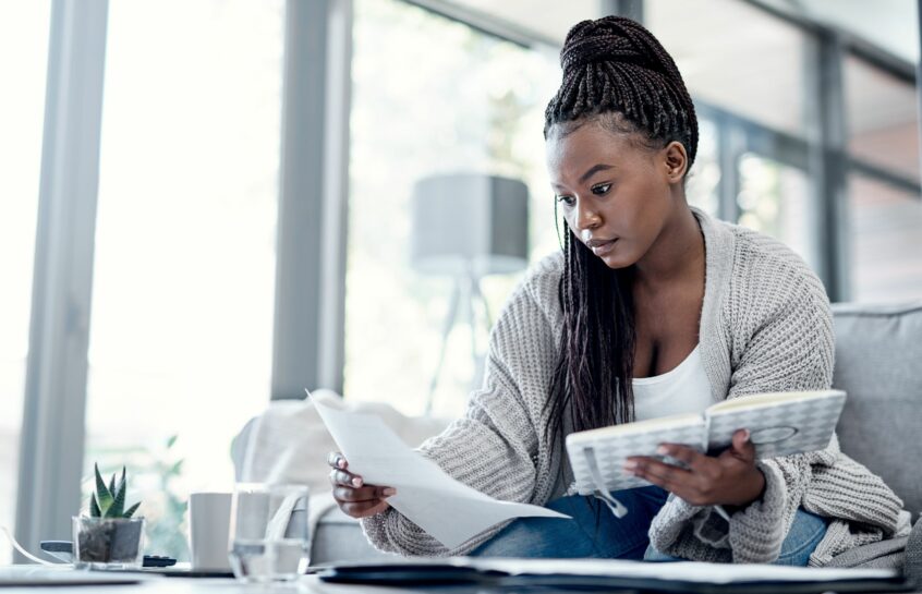 Black woman sitting on a sofa looking at a letter